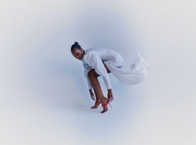 a black woman dressed in a sparkling gown with red shoes
