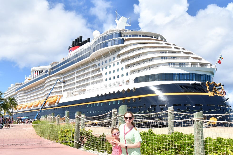 a mother and daughter posing in front of the disney wish