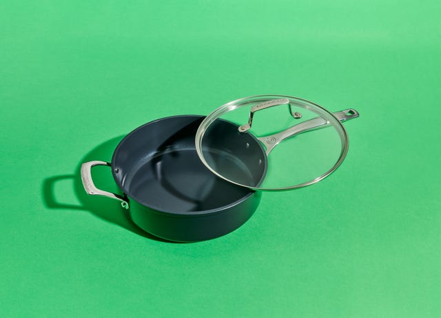 a dark cooking pot with a glass lid on a bright green background