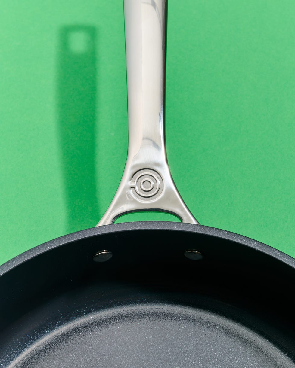 skillet with a metallic handle against a green background