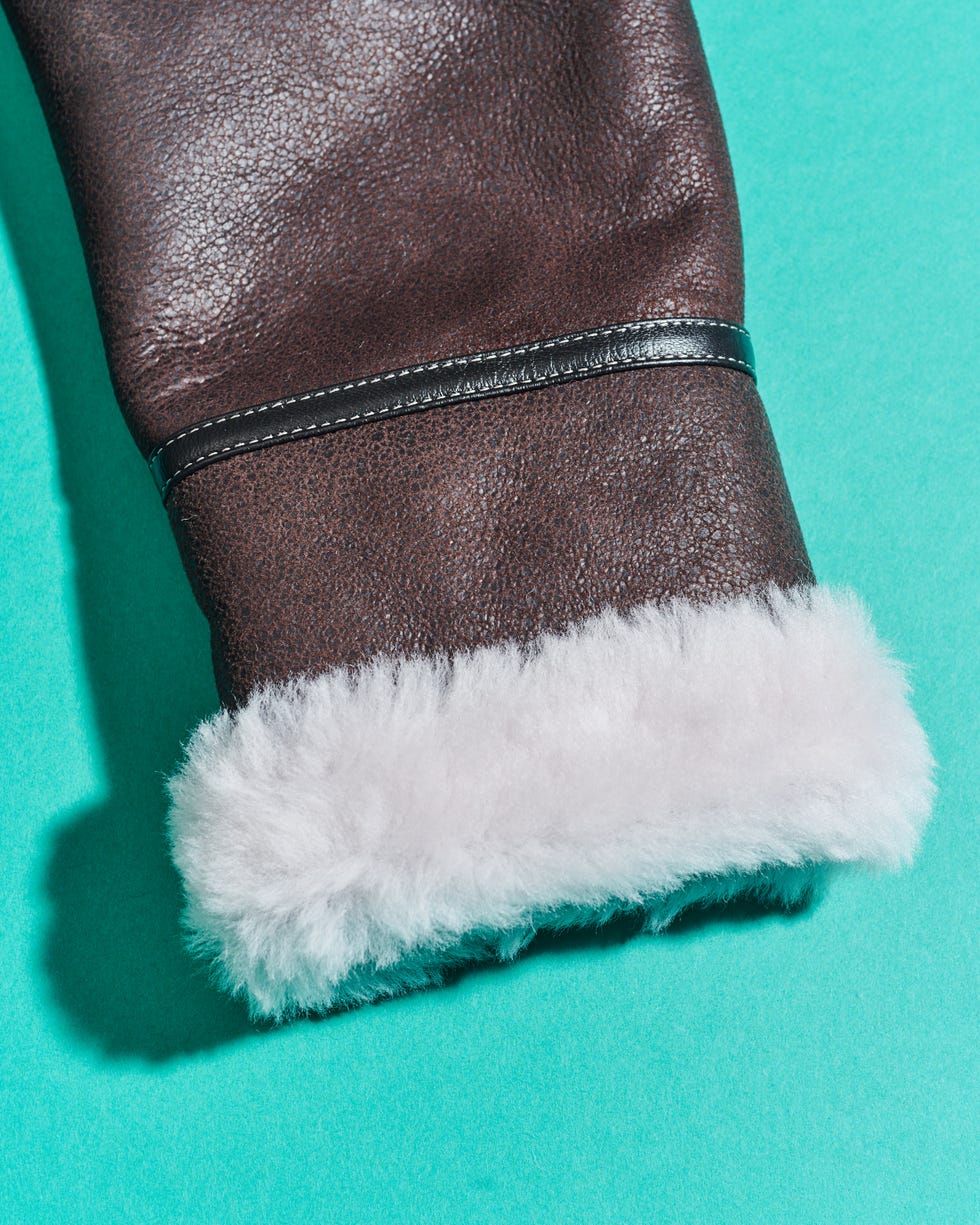 leather sleeve with a fluffy white fur lining resting on a turquoise surface