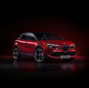 a red four door crossover with four spoke wheels sits against a black background
