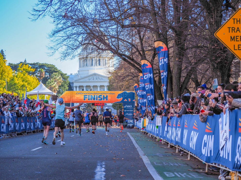 finish line of the california international marathon with runners crossing and spectators cheering
