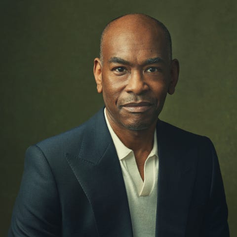 a person wearing a dark suit and a light shirt against a muted background