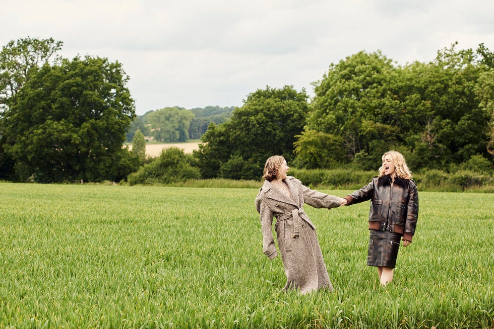two figures are walking together in a lush green field