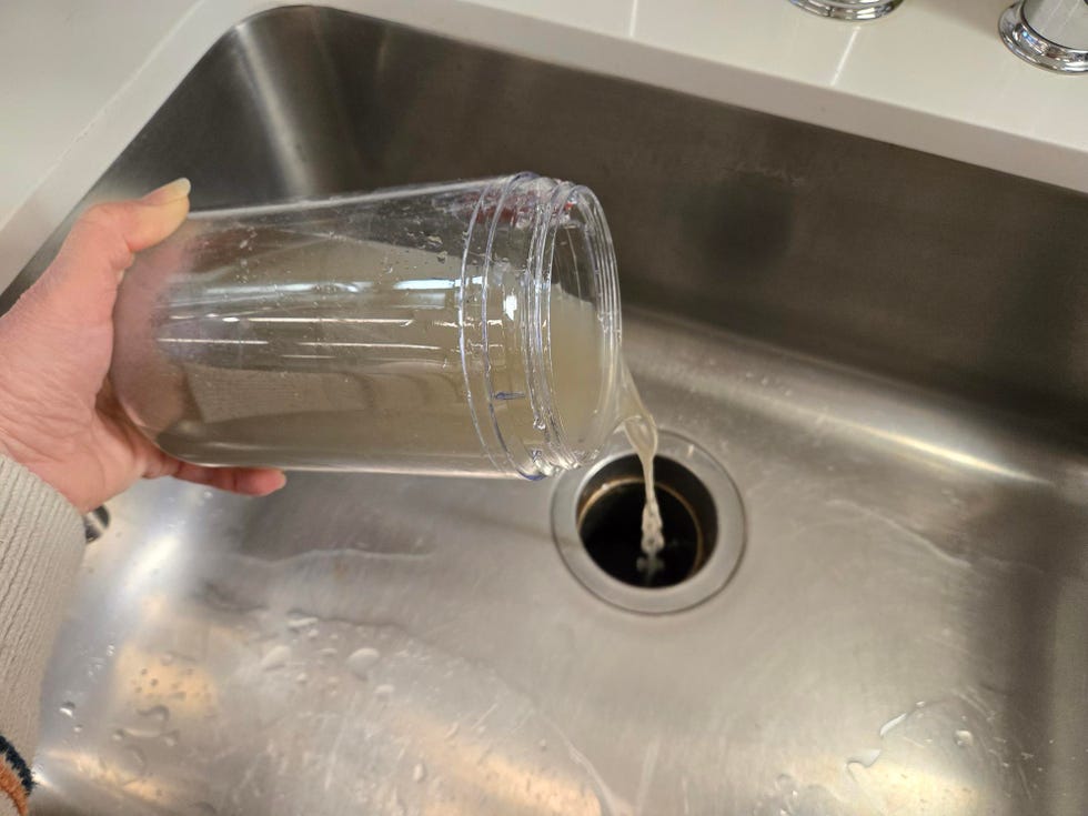 pouring a liquid from a clear container into a sink