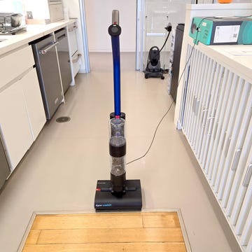 dyson washg1 wet floor cleaner positioned on a floor by a wooden threshold