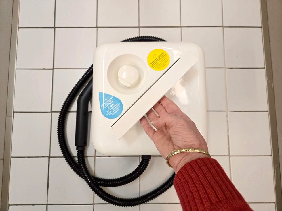 raising the handle of the dupray neat steam cleaner set on a tiled surface