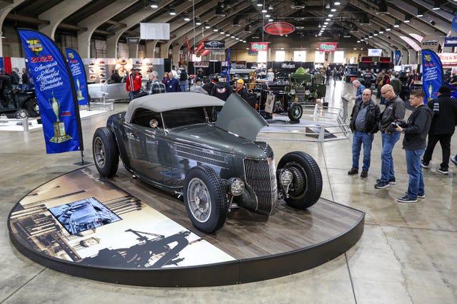 classic custom car displayed at an auto show with spectators in the background