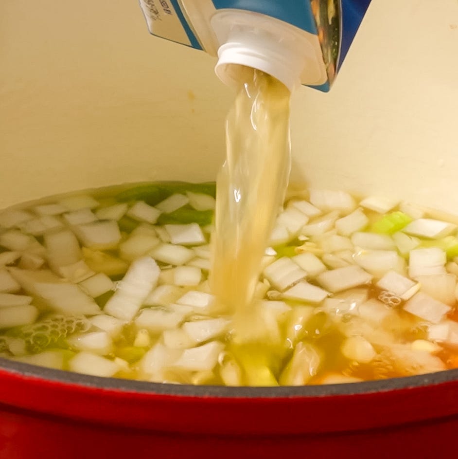 pouring liquid into a pot with chopped vegetables