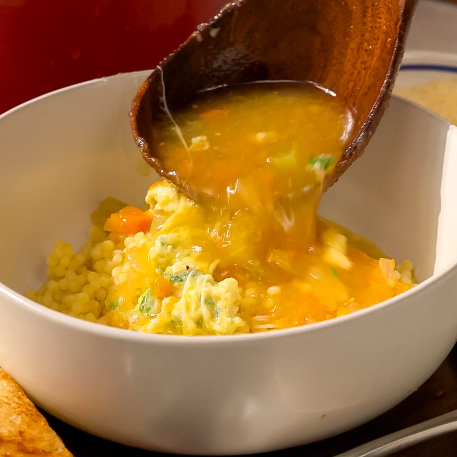 serving a savory broth over couscous with vegetables and herbs