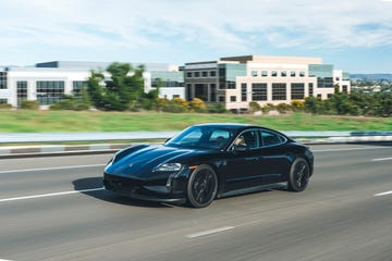 a black sports car driving on a road with a building in the background