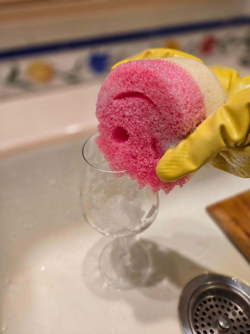 a scrub mommy sponge being wiped around a glass in a kitchen sink
