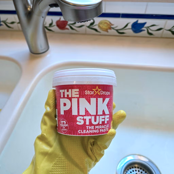 The Pink Stuff review - Hand with yellow glove holding tub of The Pink Stuff over a sink the pink stuff review hand with yellow glove holding tub of the pink stuff over a sink