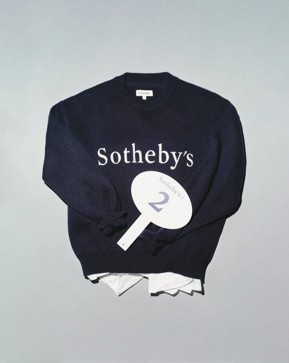 Suéter azul marino con la marca Sotheby's y un letrero con el número de subasta en blanco.