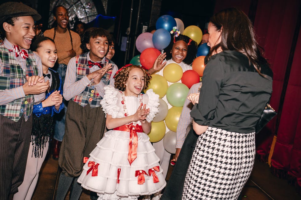 children and adults interacting at a festive event with balloons in the background