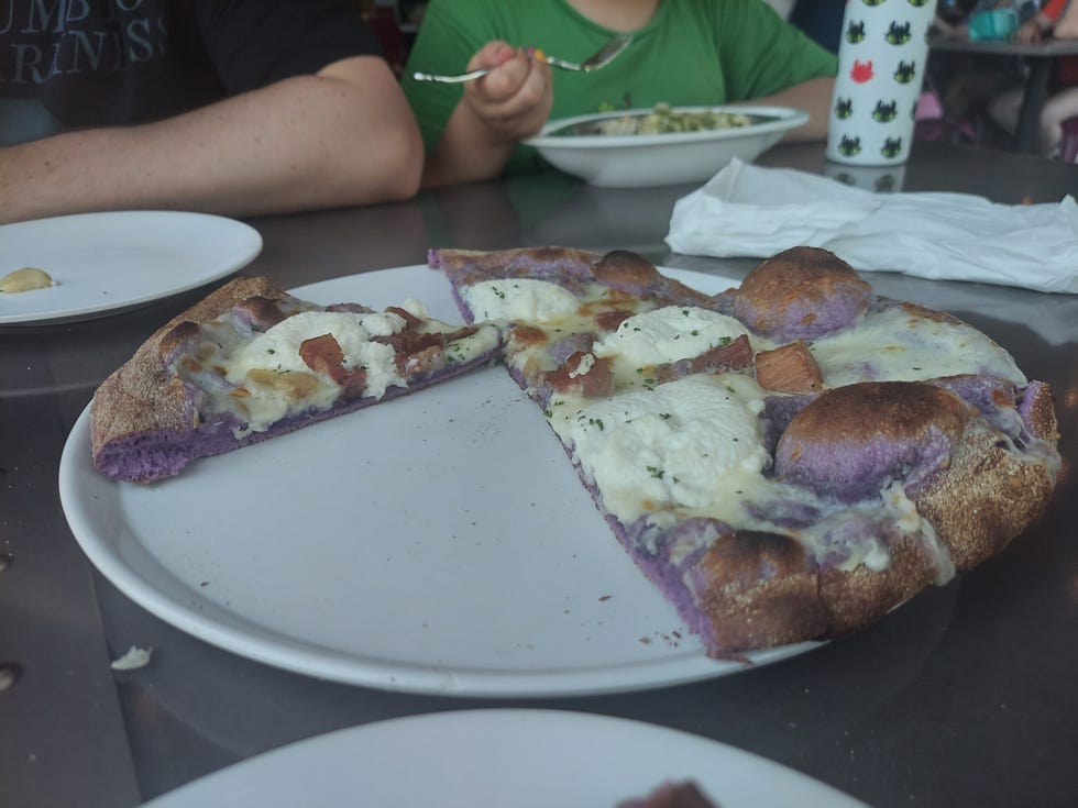 halfeaten pizza with a purple ube crust