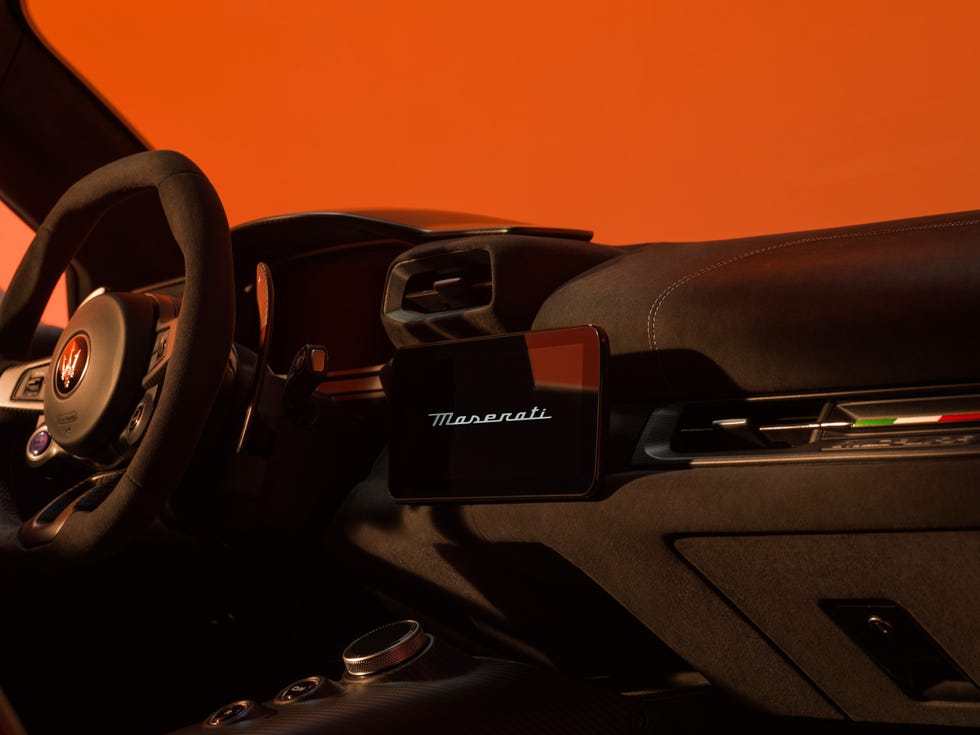 interior front view of coupe cabin showing dashboard screen, steering wheel, and accent lighting.