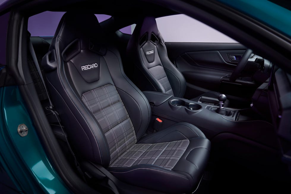 interior view of black recaro seats with plaid inserts and a manual gear shifter in a sports car.