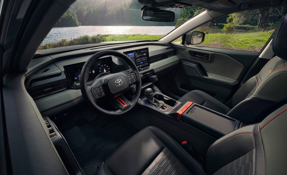 2026 Toyota RAV4 Hybrid Woodland interior interior view of a vehicle cabin featuring a digital dashboard, central touchscreen, and two tone seats with red accents.