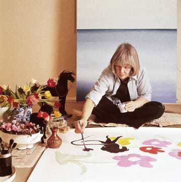 artist painting on a large canvas with surrounding floral arrangements