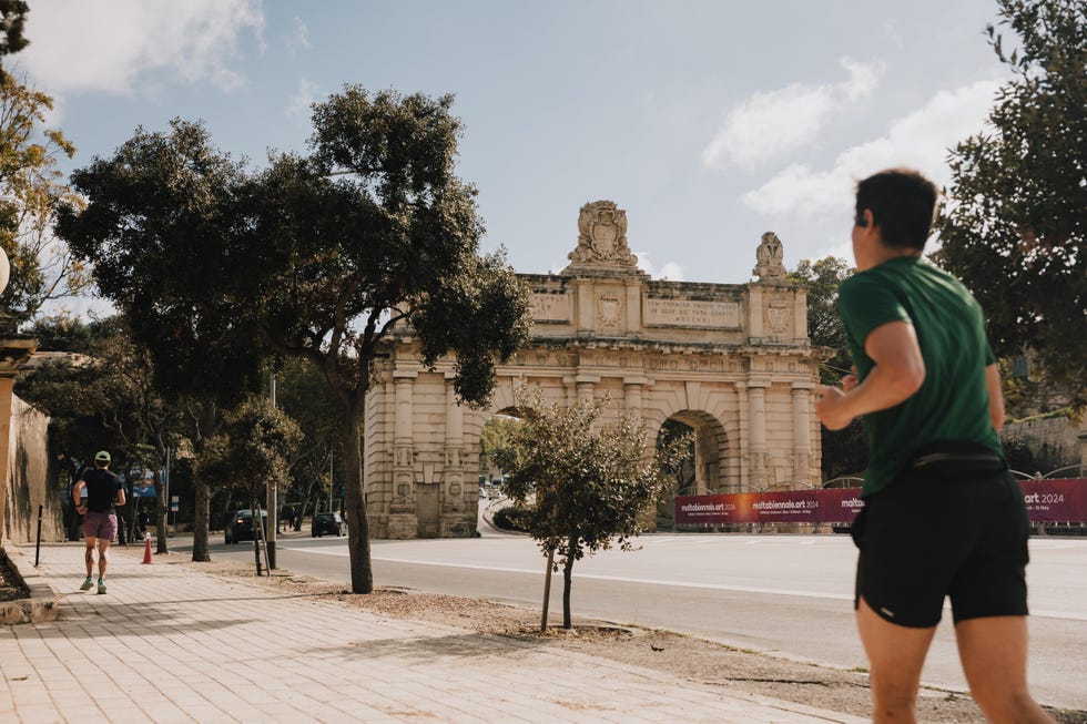 jogger running past a historical archway in an urban setting