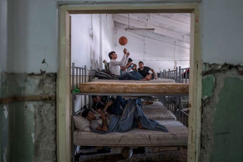 Boys play with a basketball and look at their phones inside the Obrenovac refugee center formerly used as military barracks