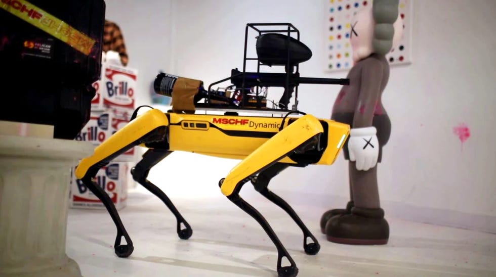 robotic dog with yellow body and black accents positioned near a stylized statue