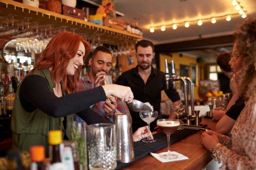 woman learning how to mix a cocktail at a lesson at a bar