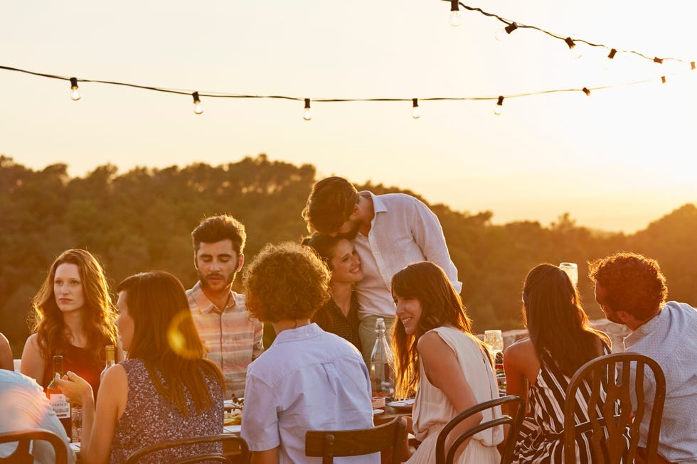 a couple cuddling and a group of friends enjoying at dinner party