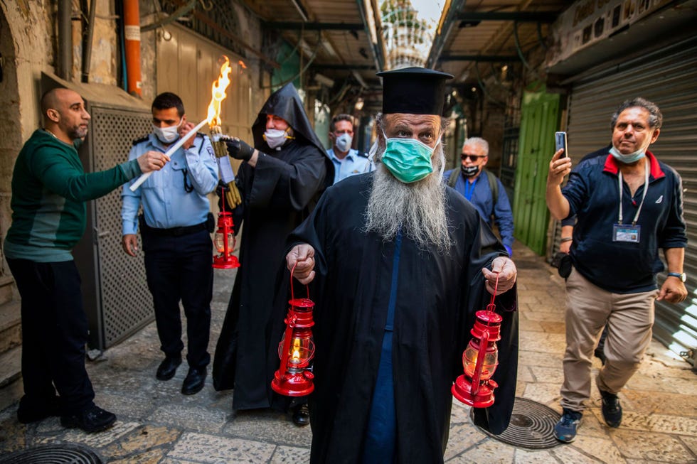 De Griekse aartsbisschop Demetrios van Lod draagt een lantaarn met daarin het Heilig Vuur door de HaNotzri de christelijke wijk van de Oude Stad van Jeruzalem Tijdens de processie van het kleine gezelschap door de uitgestorven straten kon een handvol gelukkigen de vlam overnemen