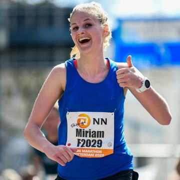 vrouw steekt duim op tijdens het lopen van haar eerste of snelste marathon