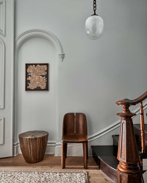 an entryway with a chair and pendant light next to a staircase