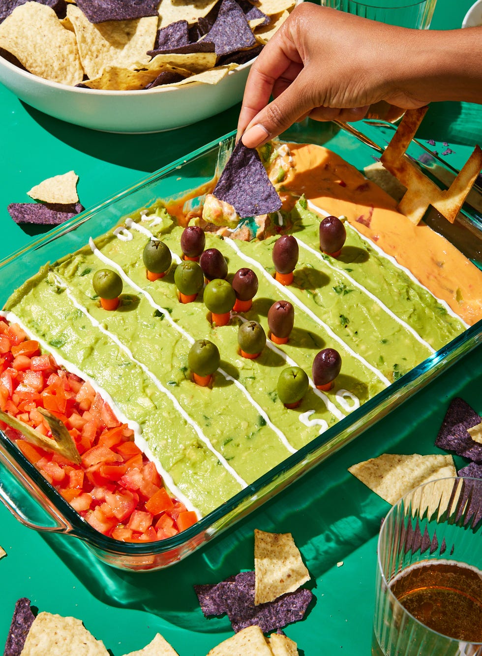football field decorated layered dip with refried beans, sour cream, pico de gallo, guacamole, and queso