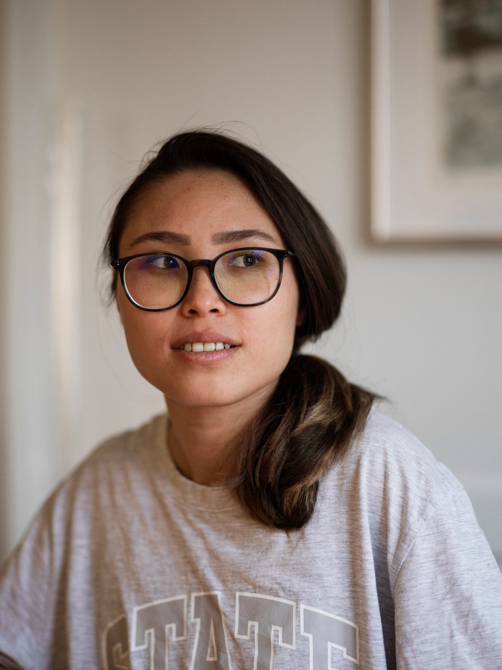 a person with dark hair weating a t shirt with the word state poses for a portrait