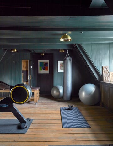 gym in the eaves of an attic with wood panelling painted a dark petrol blue