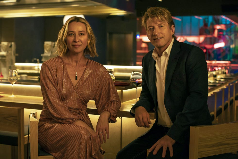 two individuals seated at a bar in an upscale setting