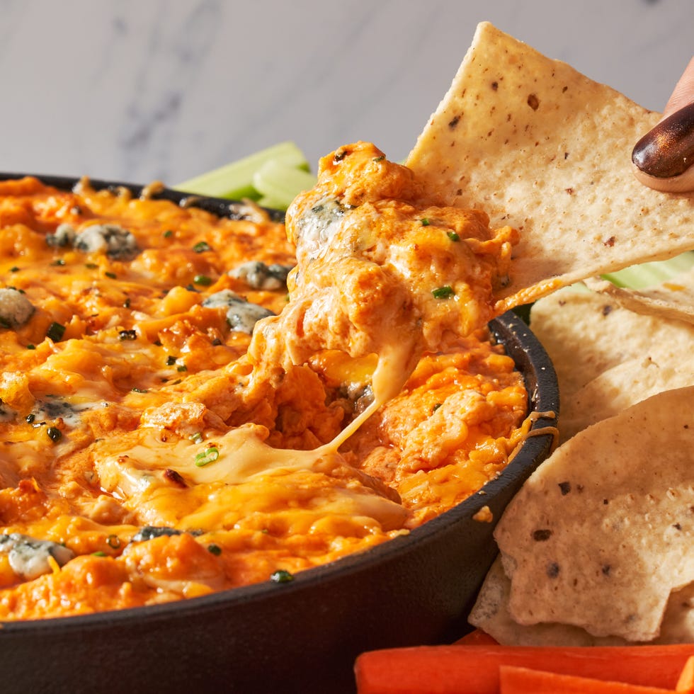 buffalo chicken dip in a skillet with a chip dipping some out