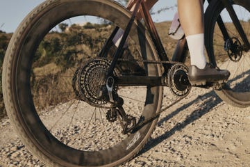 achterwiel van een fiets en benen van een wielrenner in beeld