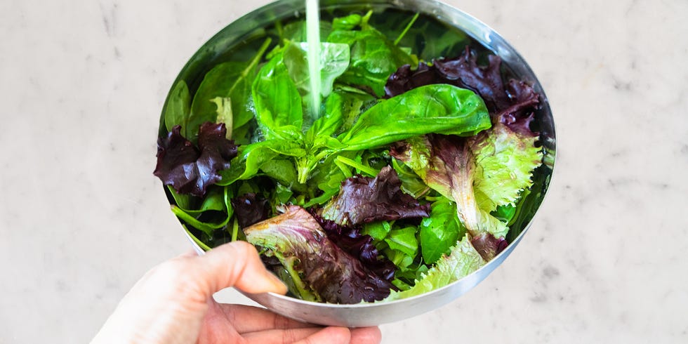 a hand holding a bowl of salad