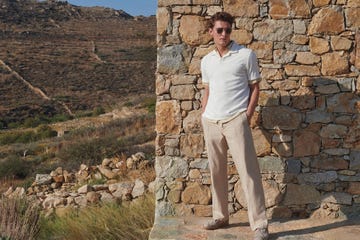 a man standing next to a stone wall