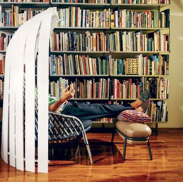 a person sitting on a chair in front of a book shelf