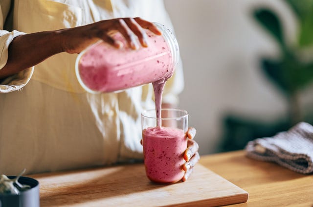 a person pouring a drink into a glass