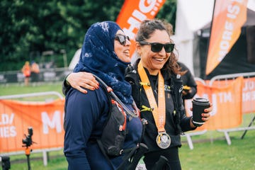 Two women celebrating after a race one holding a coffee and the other wearing a medal