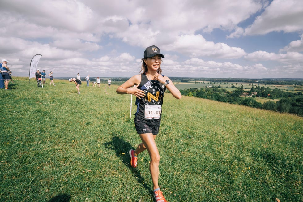runner participating in an outdoor event on a grassy hillside with spectators in the background