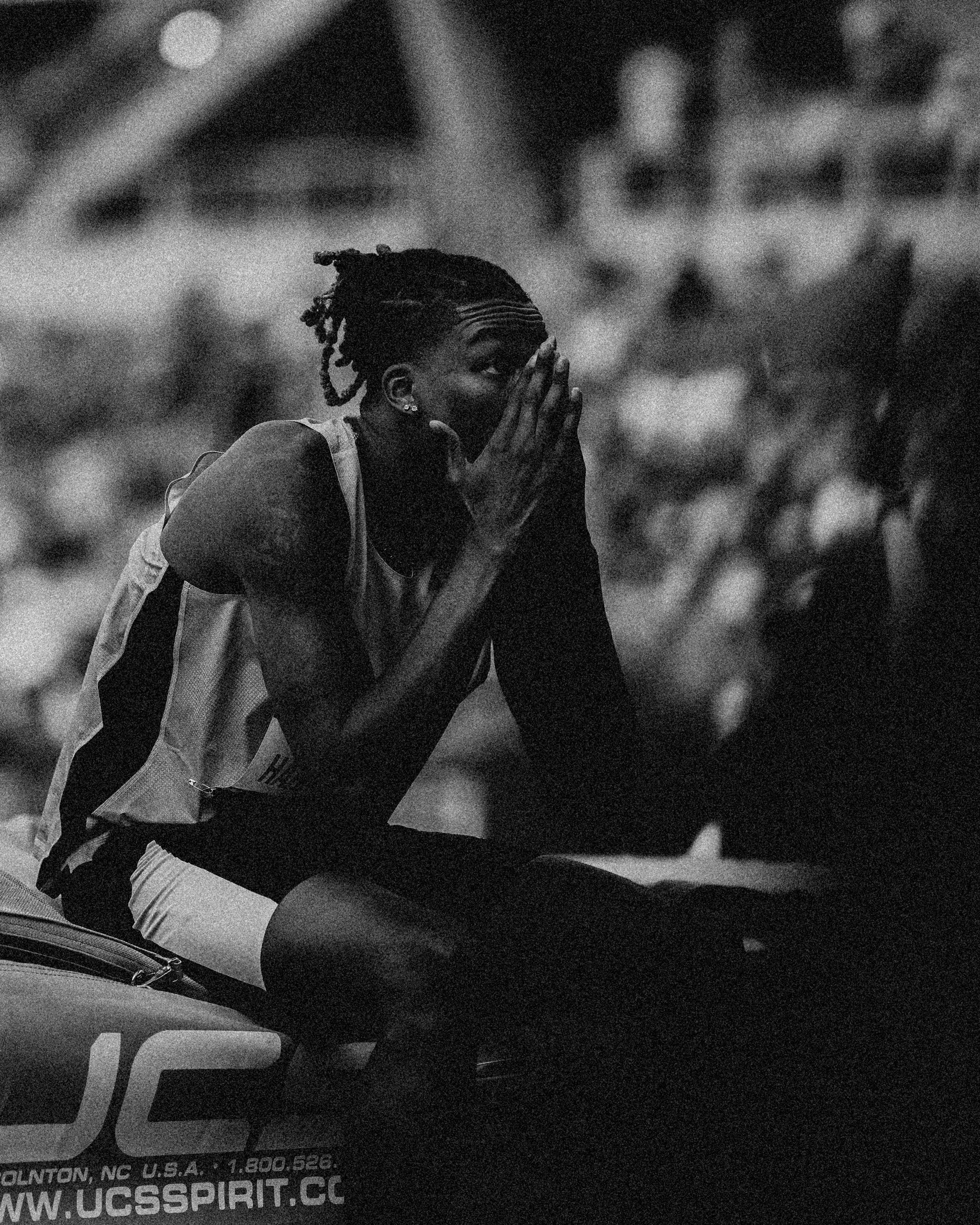 a male track and field athlete covers his face with his hands