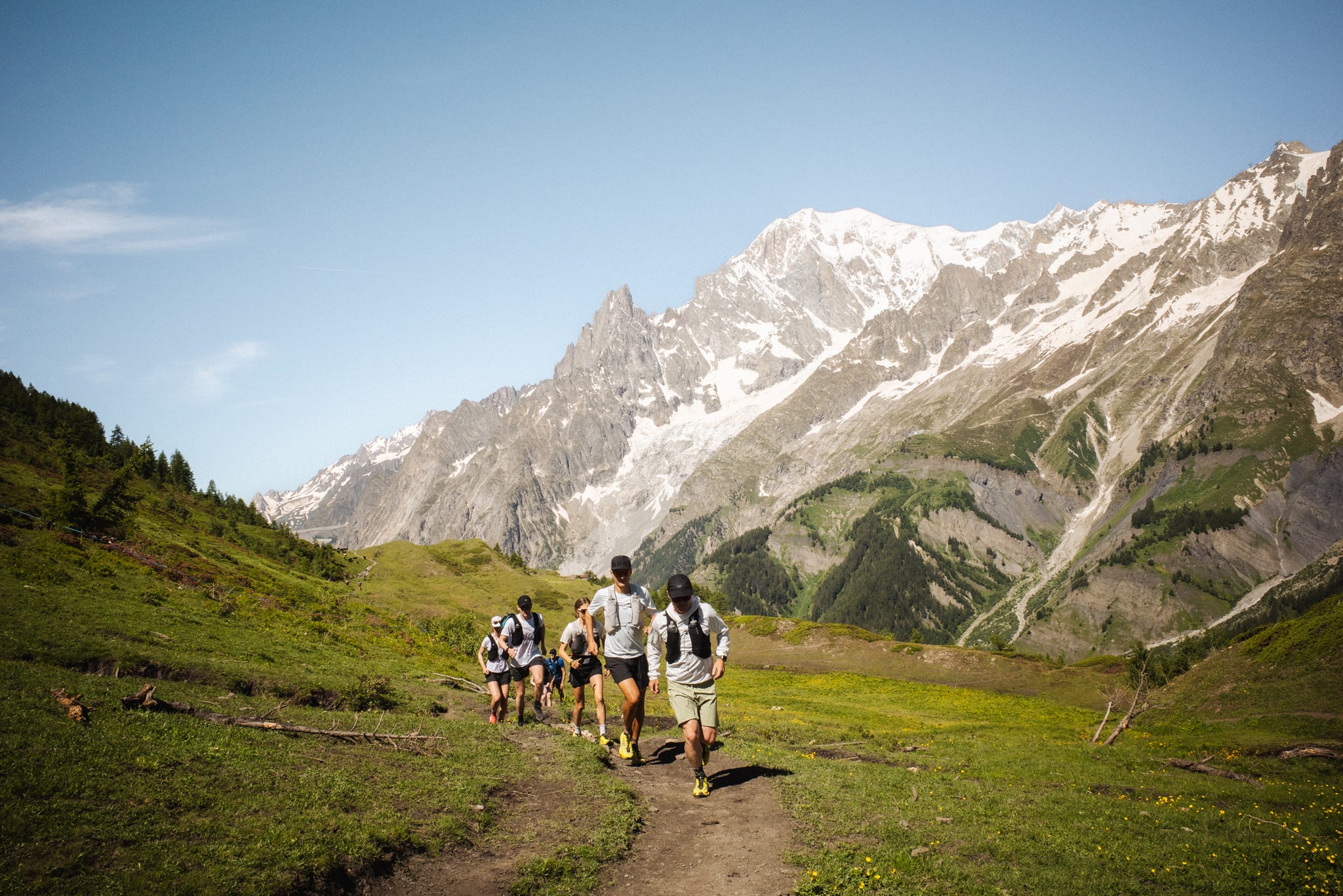 runners on a trail against a back drop of mountains and green fields