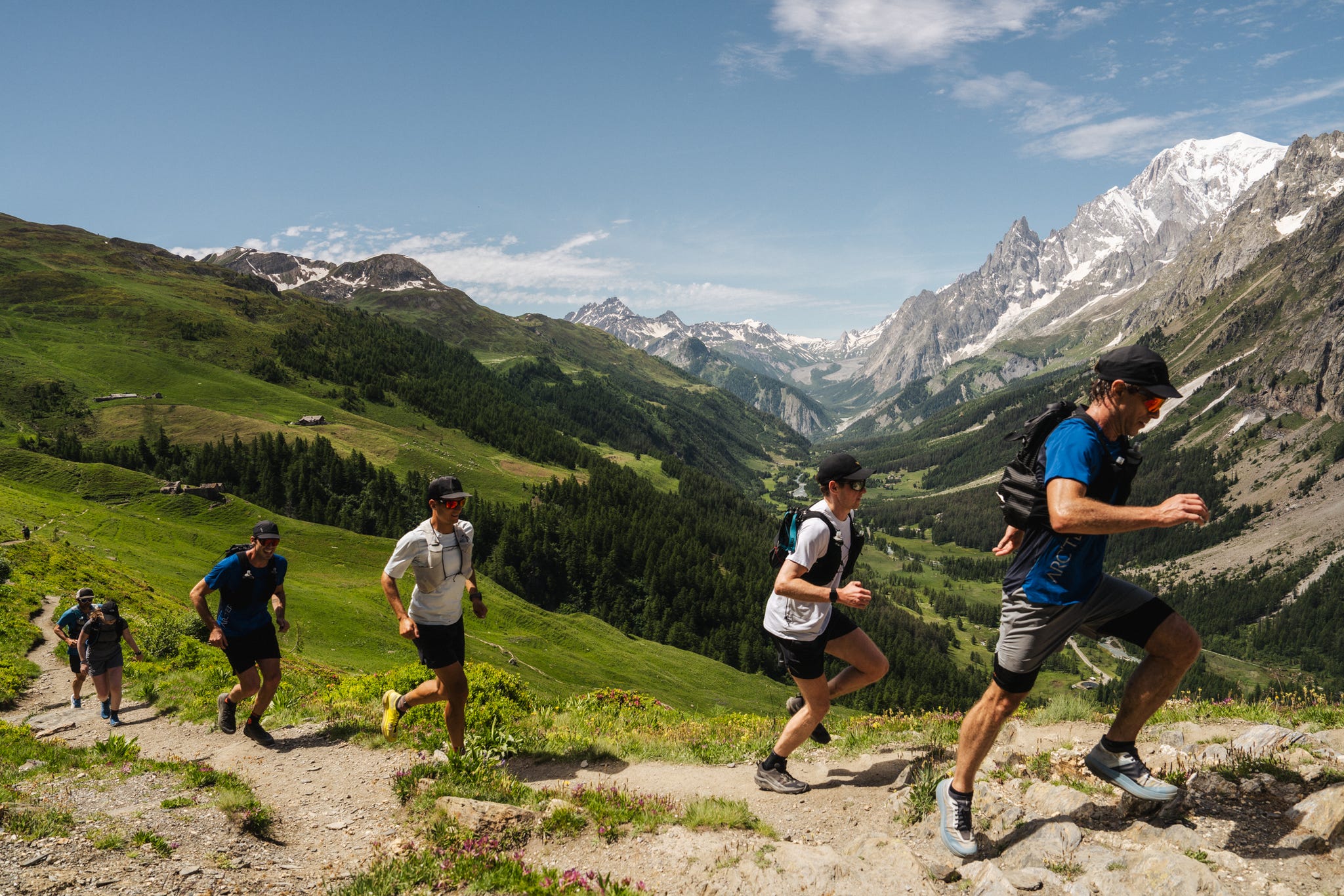 a line of runners on a trail in the mountains