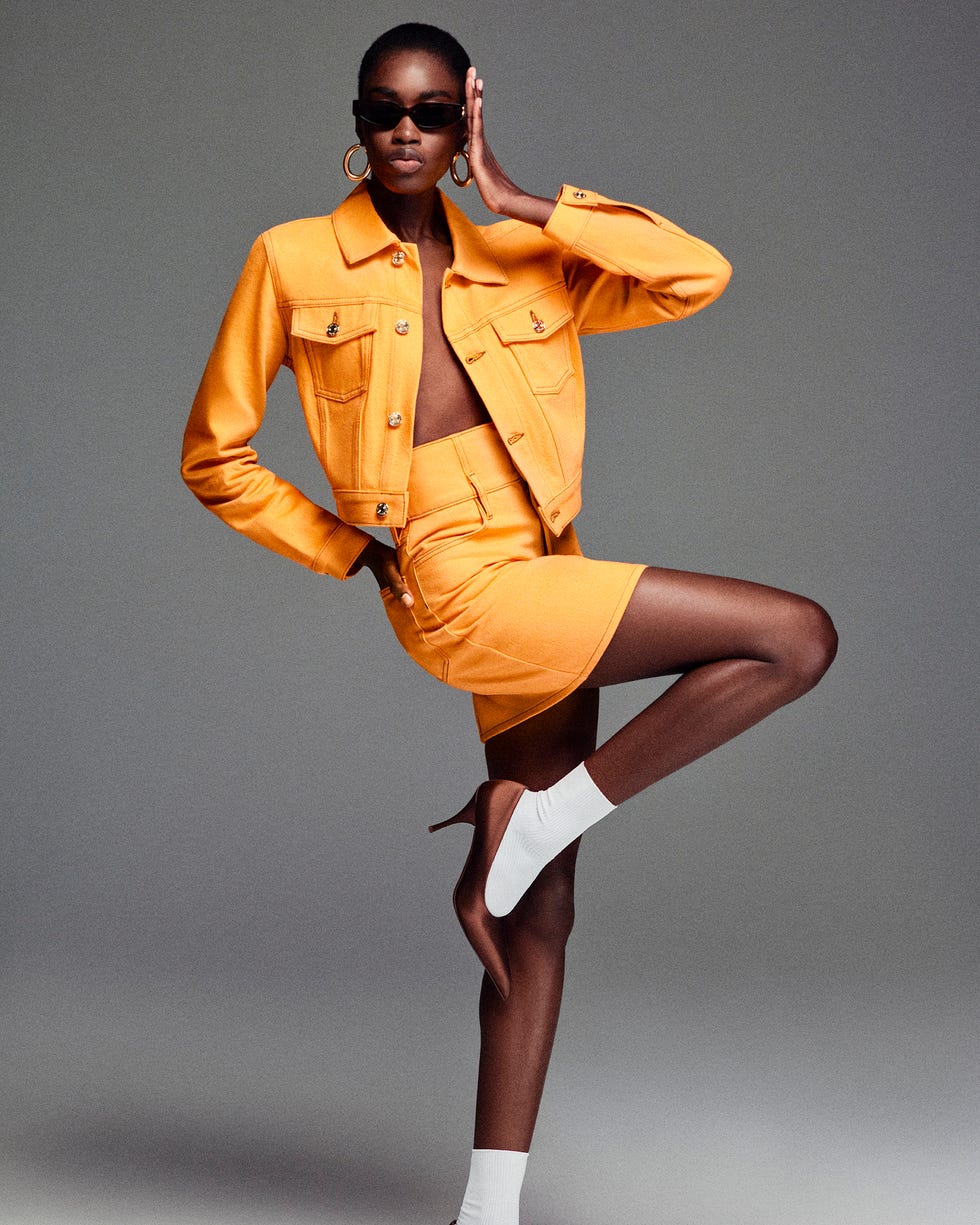 model wearing a yellow denim jacket and matching skirt striking a pose