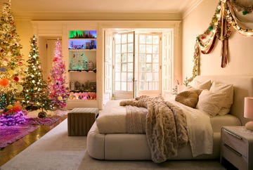 bedroom with plush bedding, a neon pink christmas tree, and shelves that have led lighting of many colors and christmas tchotchkes resting on top